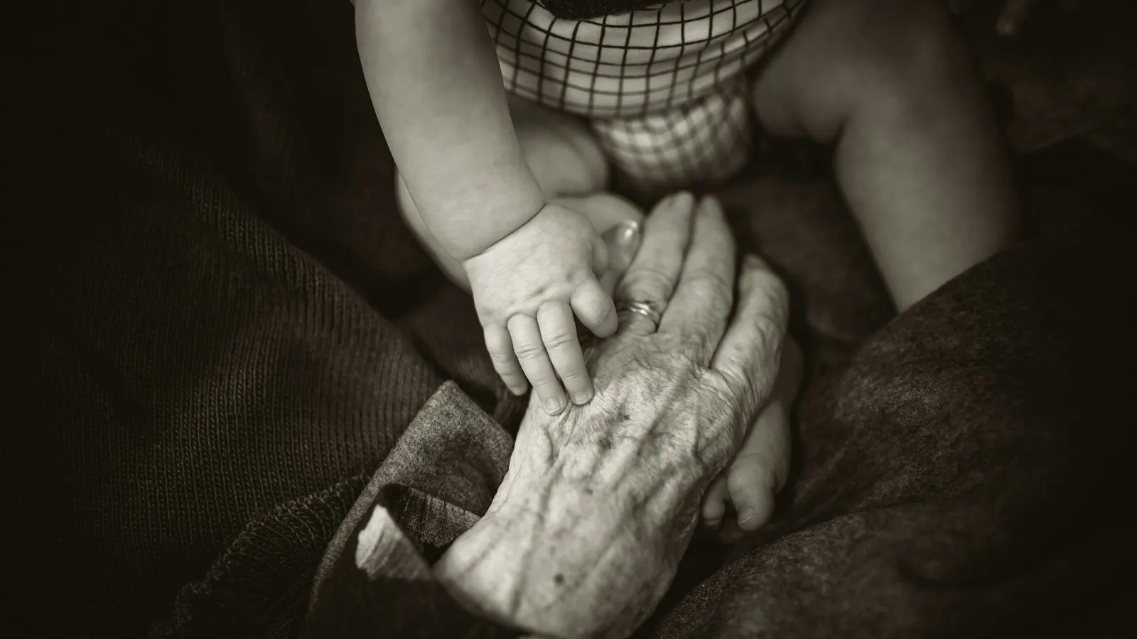 An older woman holding a baby's hand