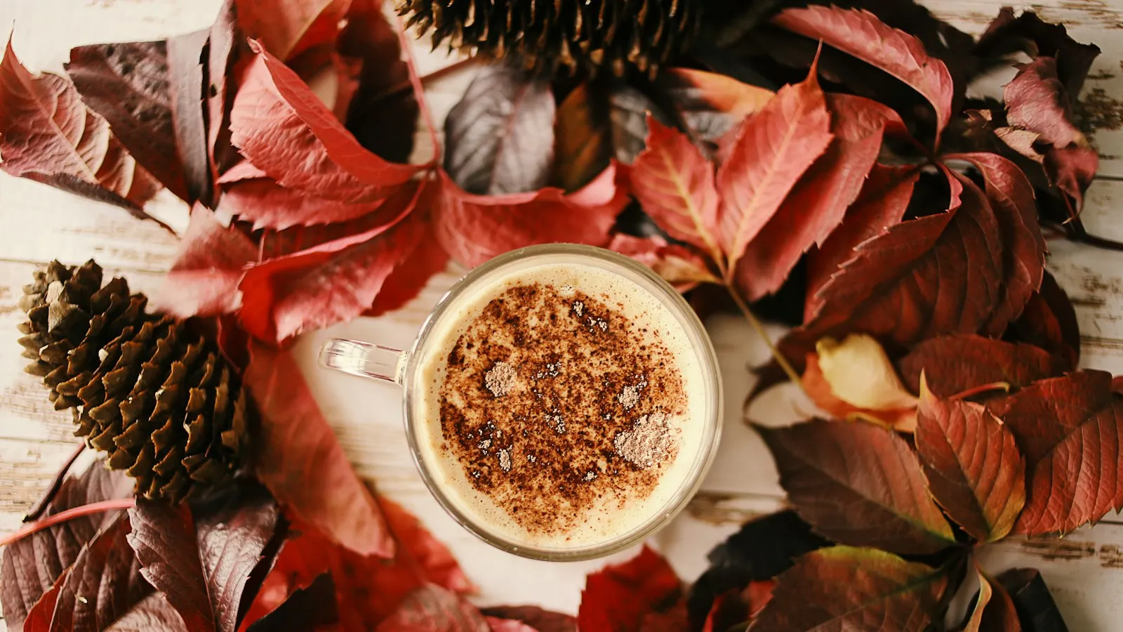 A cup of coffee among red autumn leaves
