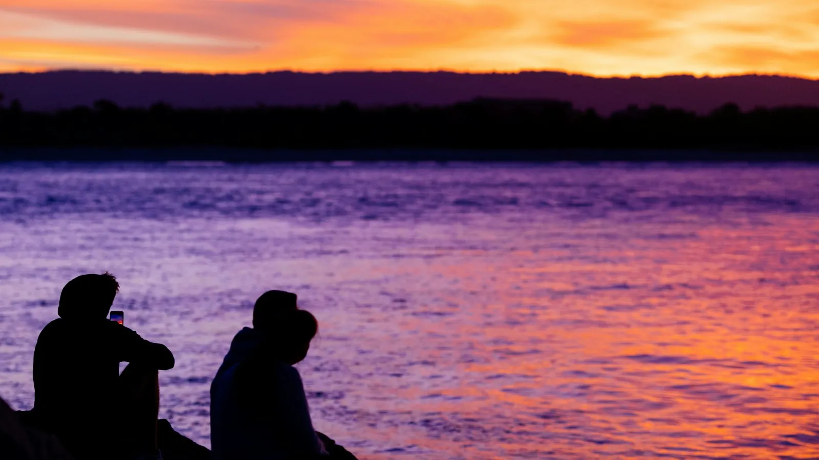 Two people on a dock watching the sunset