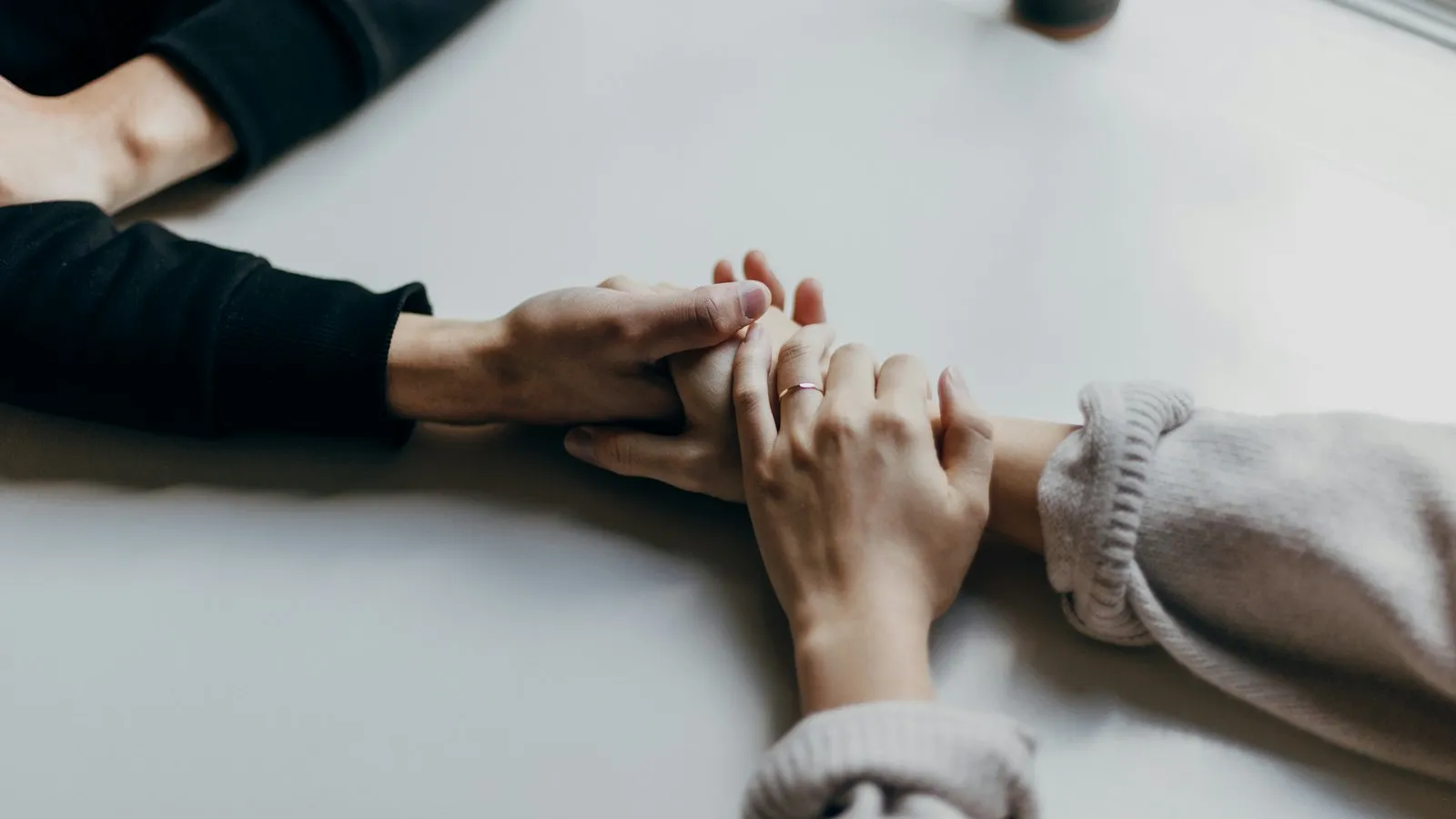 Two people holding hands across a table