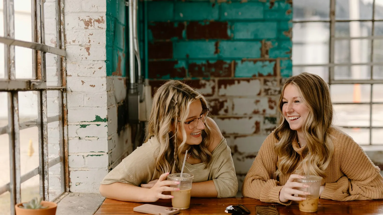 Two friends talking over drinks at a café table