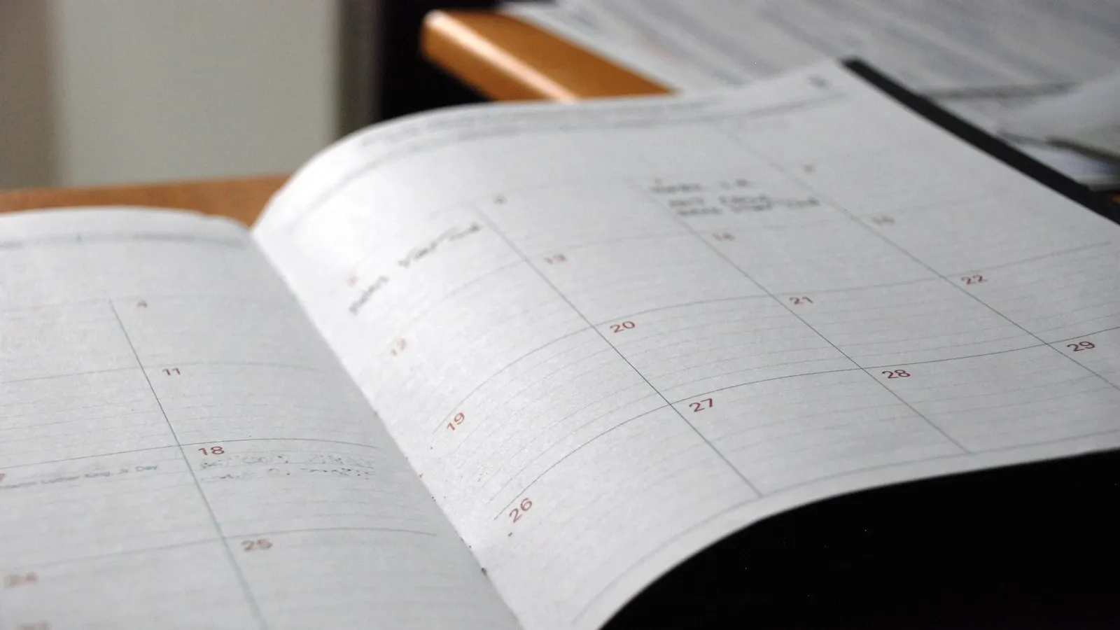 An open monthly planner on a wooden desk