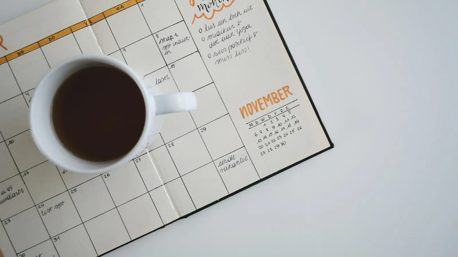A cup of coffee resting on an open planner