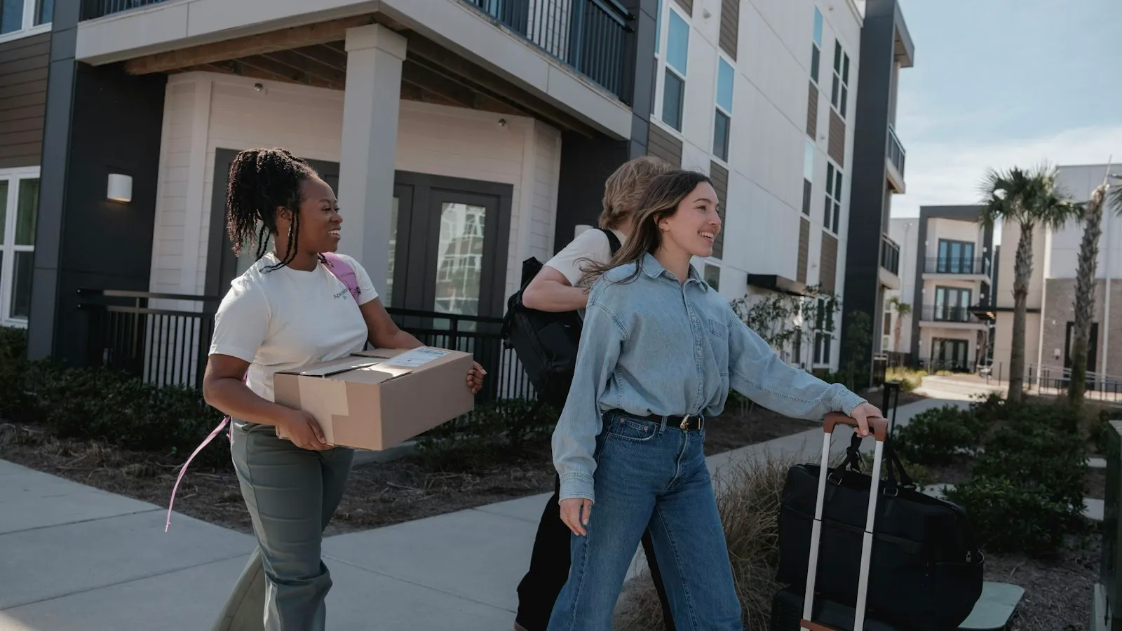 Young people carrying boxes outside an apartment