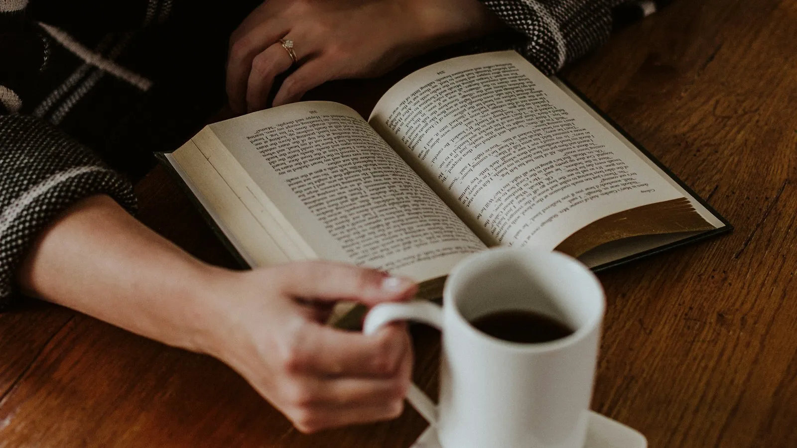 Someone sitting on the floor with a book and a cup of coffee