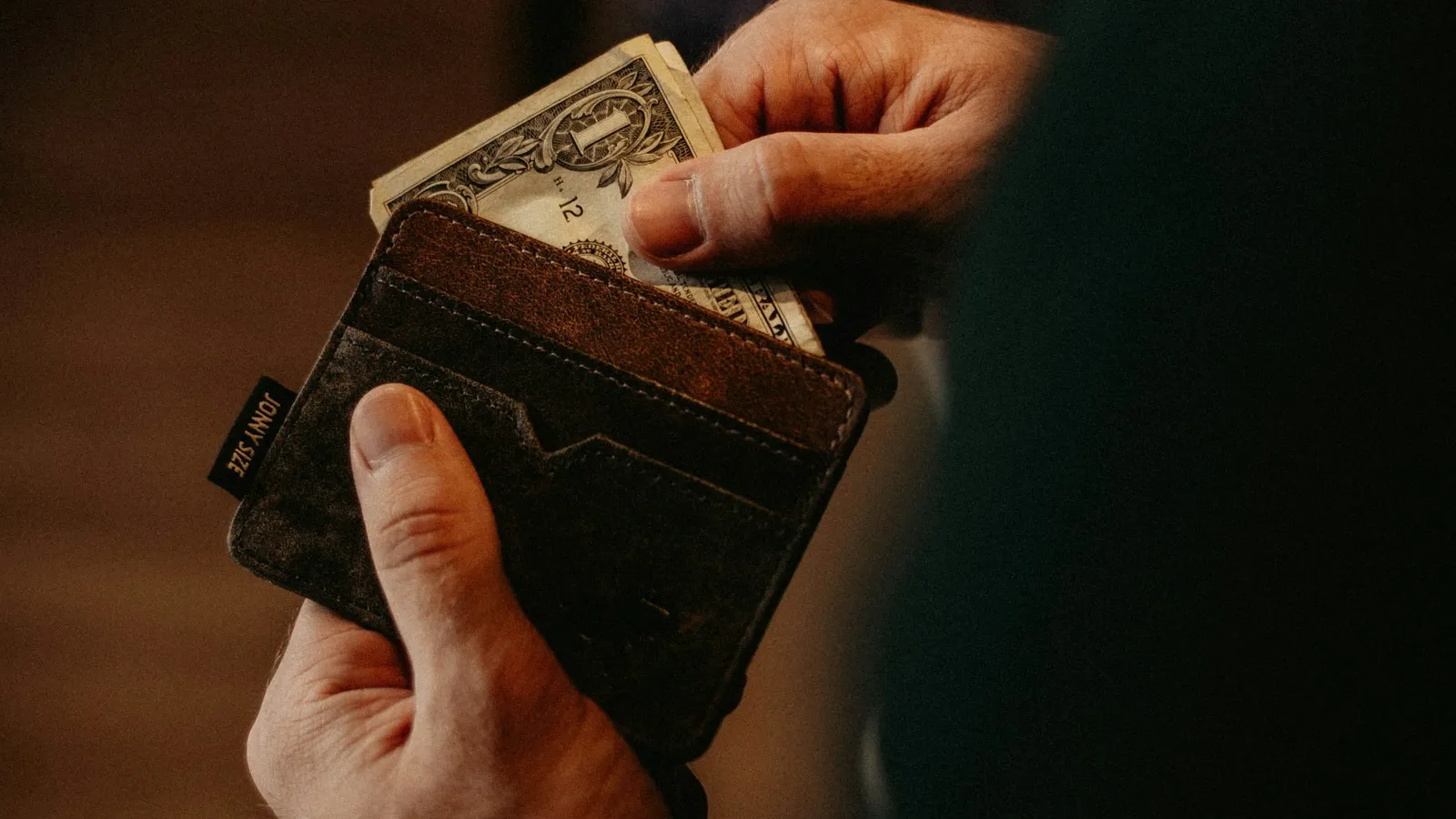 Someone taking a dollar bill out of a wallet