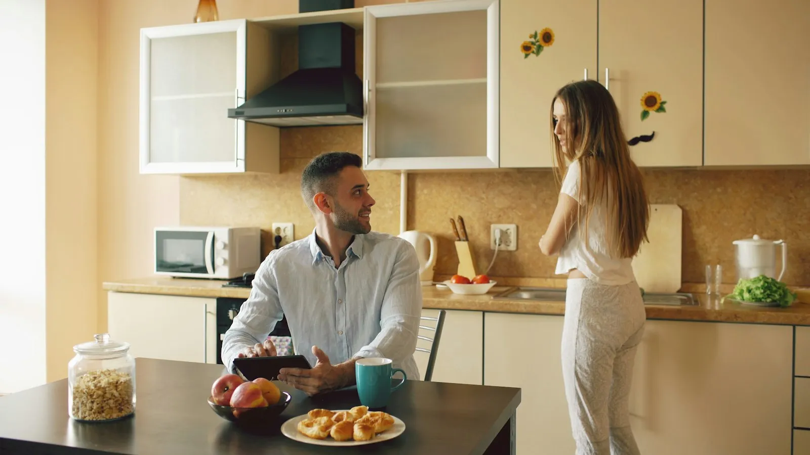 Two people talking in a kitchen over breakfast