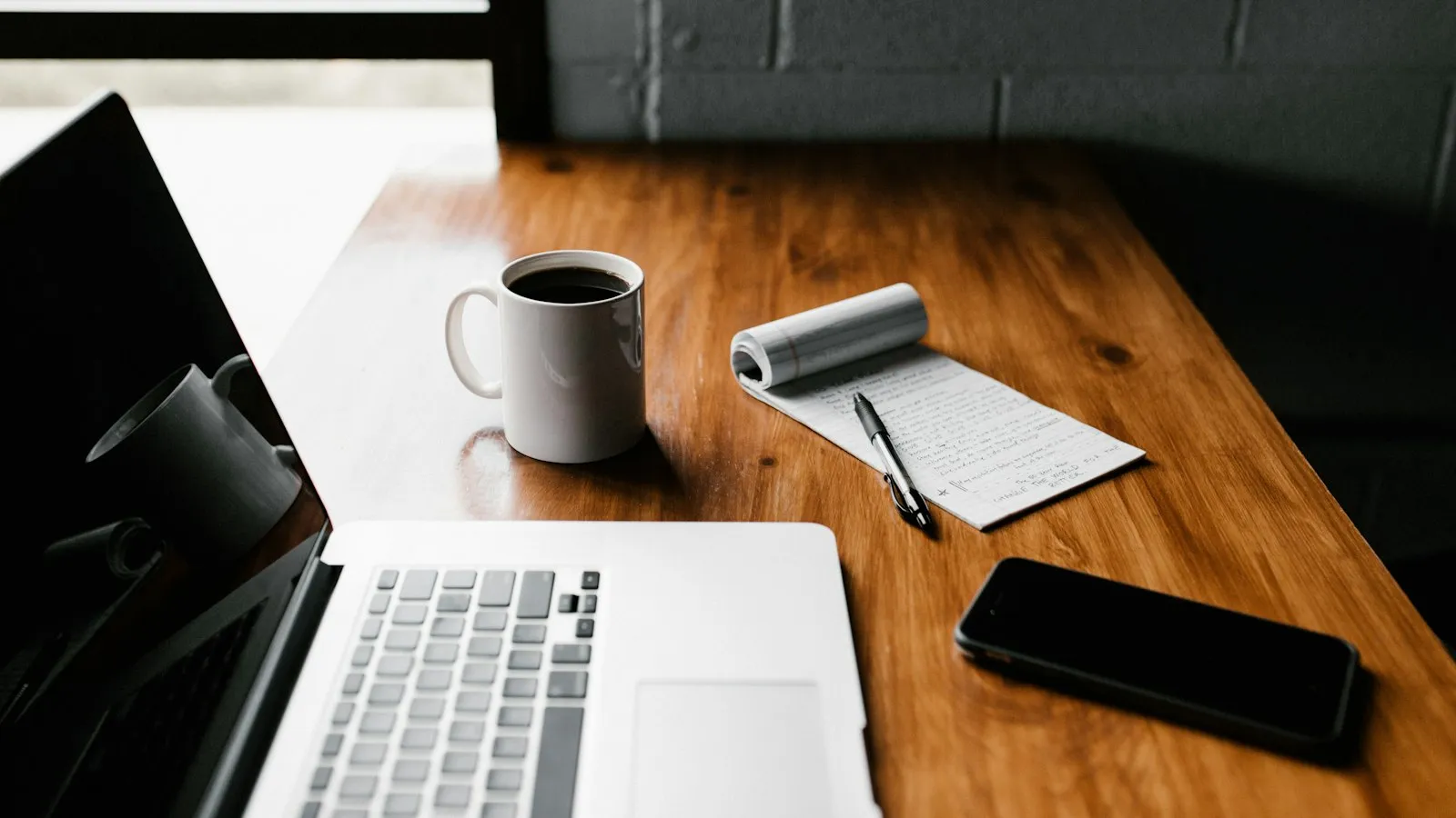 A laptop, a mug and a phone on a desk
