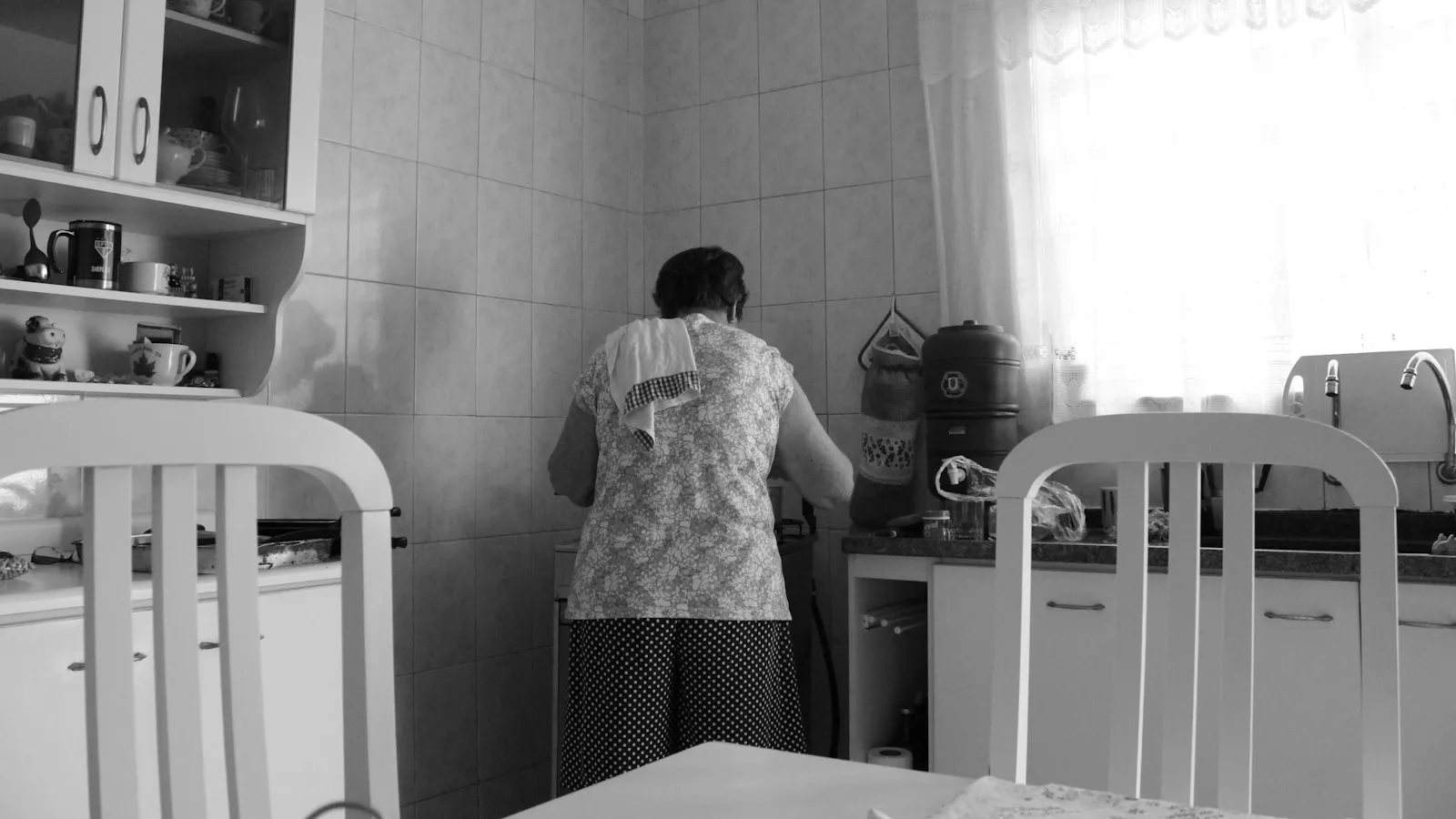 A black-and-white photo of a woman in her kitchen