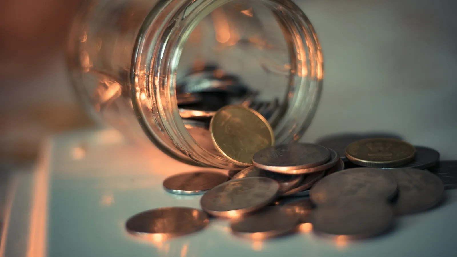 A glass jar partly filled with coins